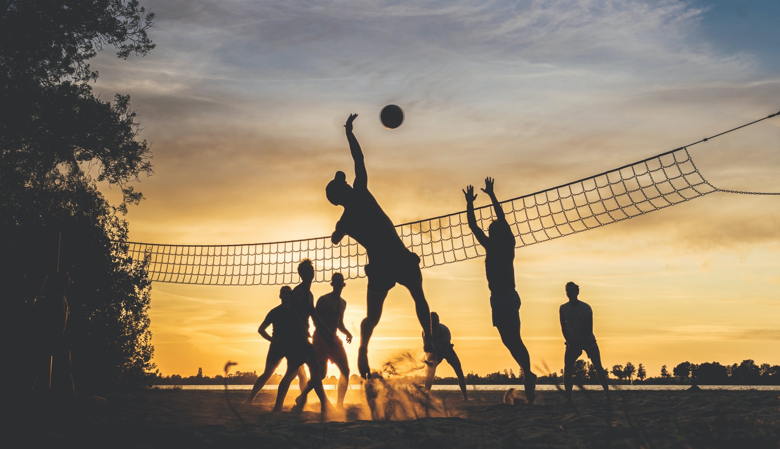 personnes jouant au volley au coucher du soleil